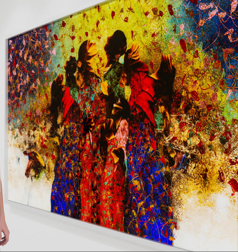 A vibrant abstract painting featuring three figures dressed in bold red and blue garments, surrounded by intricate swirling patterns and scattered leaves. The background transitions from a golden yellow at the top to deep blue on the right, with rich textures and organic shapes creating a sense of movement and energy. The figures' faces are obscured, adding a layer of mystery to the composition.