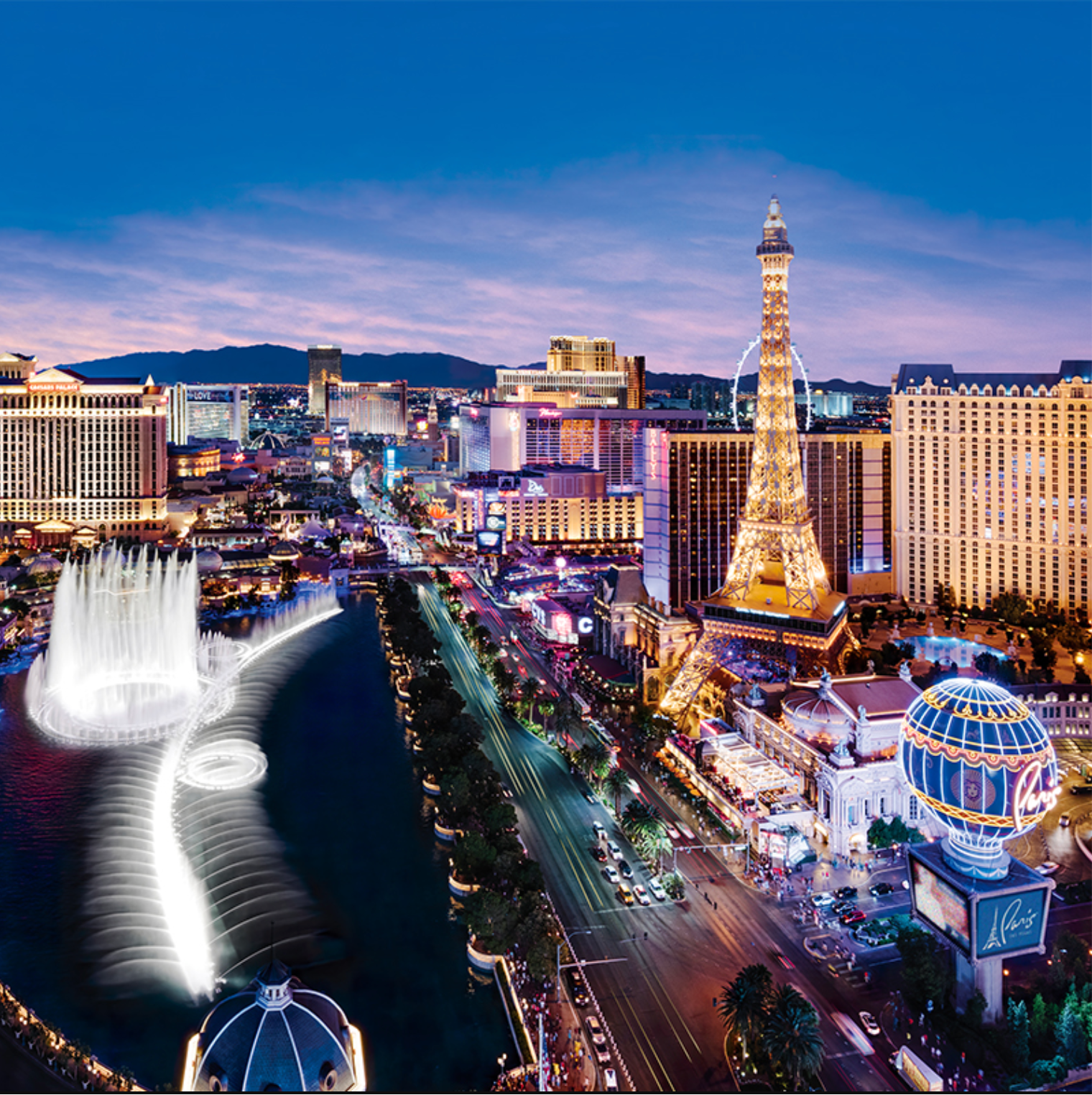 A dazzling view of the Las Vegas Strip at dusk, featuring bright neon lights, iconic hotels, and attractions. The image showcases the Bellagio Fountains in action, with arcs of water illuminated against the darkening sky. To the right, a replica of the Eiffel Tower, lit with golden lights, stands prominently alongside the Paris Las Vegas Hotel. The scene is bustling with activity, as cars line the streets and the skyline glows with colorful lights, creating a vibrant and energetic atmosphere.